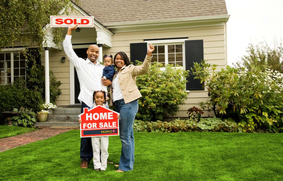 Young family in front of home with a sold sign.