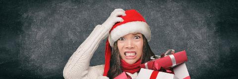Stressed woman wearing a Santa hat and holding holiday gifts.