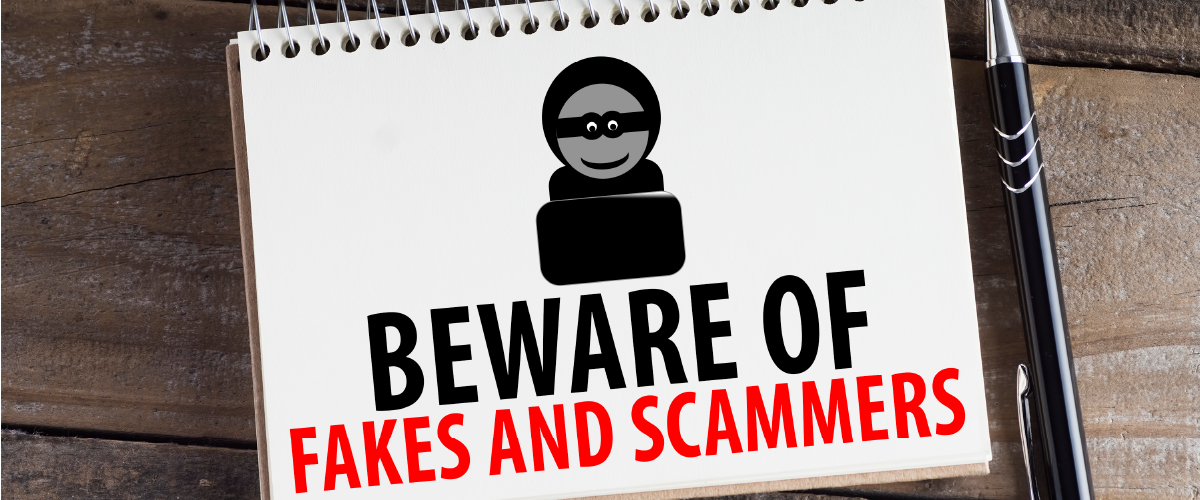 Notepad with the words "beware of fakes and scammers" sitting on a table with a pen