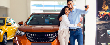 A couple holding the keys of their new car, standing in front of the car