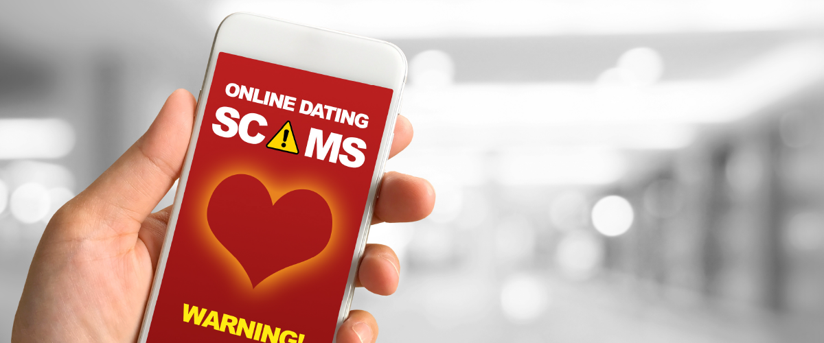 Person holding up a phone that warns against online dating scams