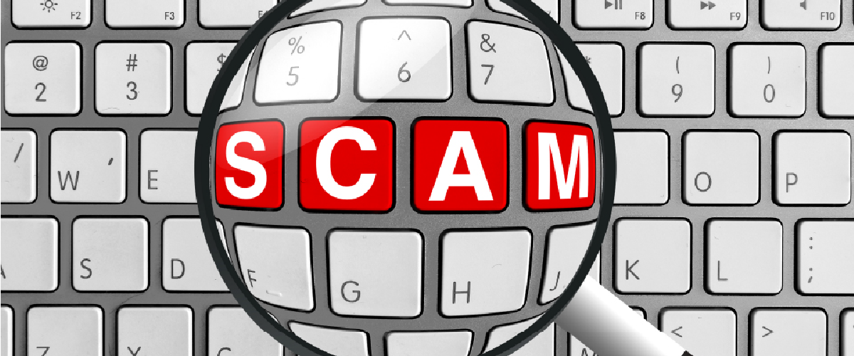 Magnifying glass over the word "Scam" on a keyboard