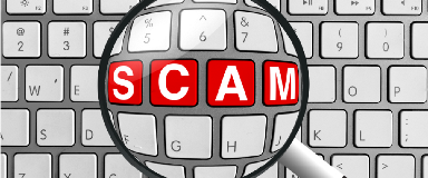 Magnifying glass over the word "Scam" on a keyboard