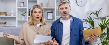 Older couple holding papers and looking surprised