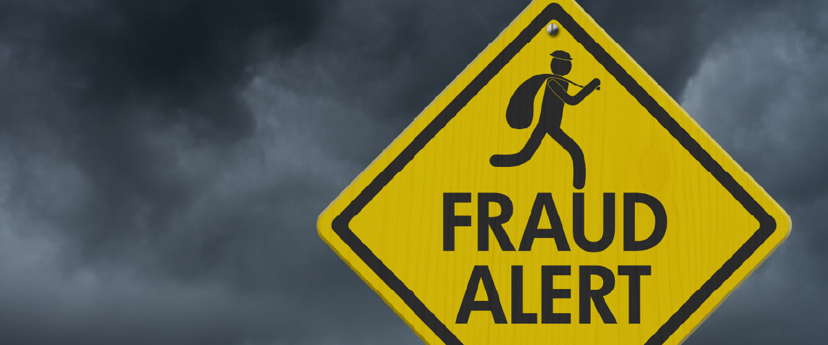 Yellow sign that says "Fraud Alert" with dark storm clouds in the background.