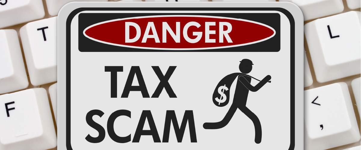 Sign that indicates a dangerous tax scam on top of a key board