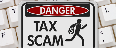 Sign that indicates a dangerous tax scam on top of a key board