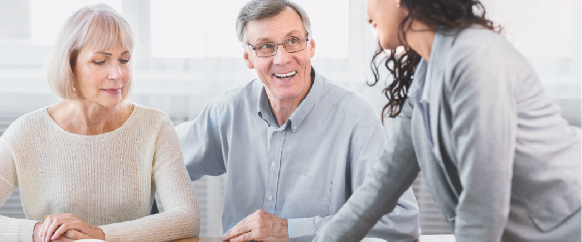 Two older people meeting with a professional and looking at documents