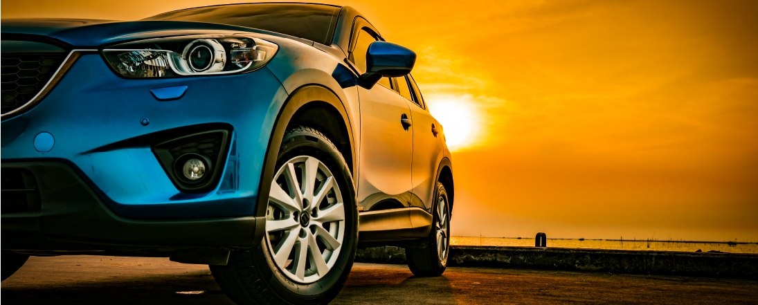 Blue car with sun setting behind it