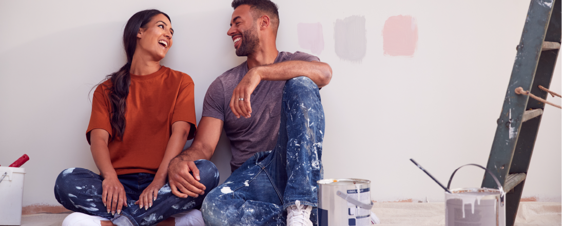 Young couple taking a break from painting the wall of their house
