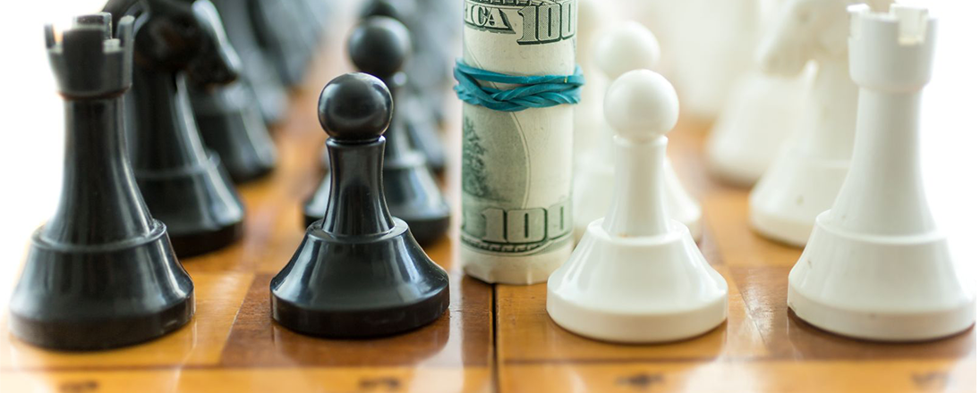Chess board with a roll of 100 dollar bills