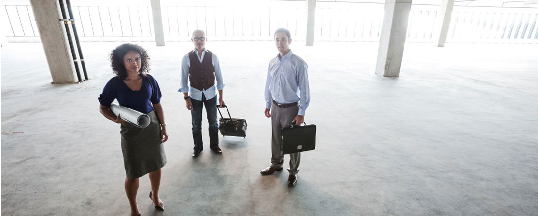 Three business people with blueprints in a building