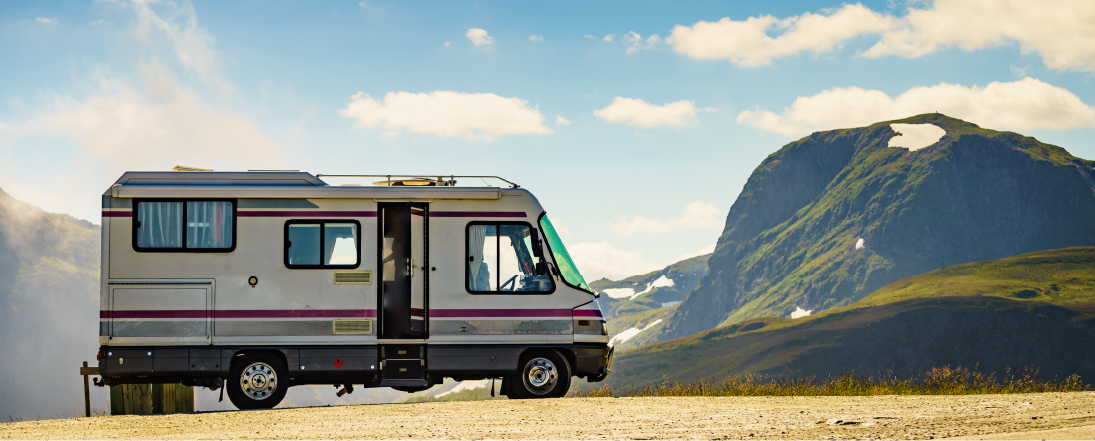 RV parked on a road with a mountain in the background