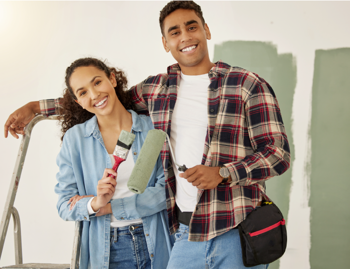 Couple standing together with paint brushes, painting house