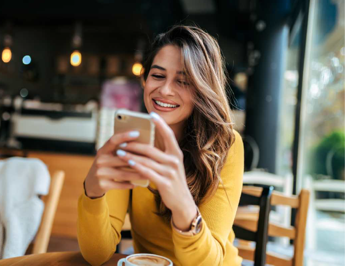 Young woman drinking coffee and looking at her phone
