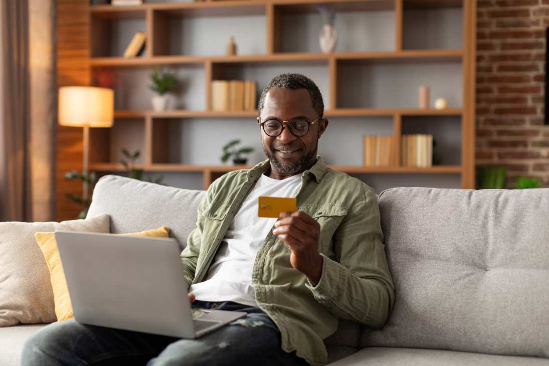 Older man with a bank card in hand and laptop