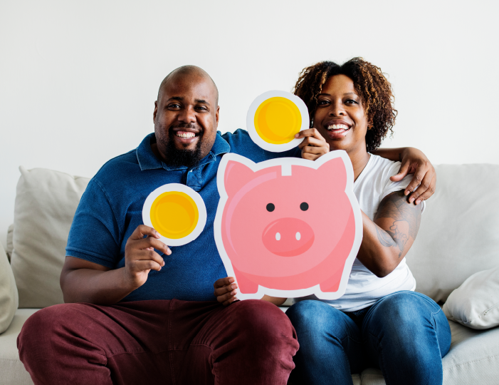 Couple sitting on couch holding large coins and piggy bank