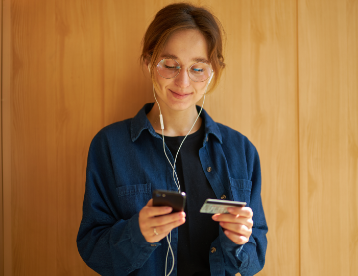 Woman looking at phone and using a credit card